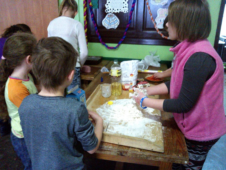 Dzieci przy stolnicy robią ciasto na pizze